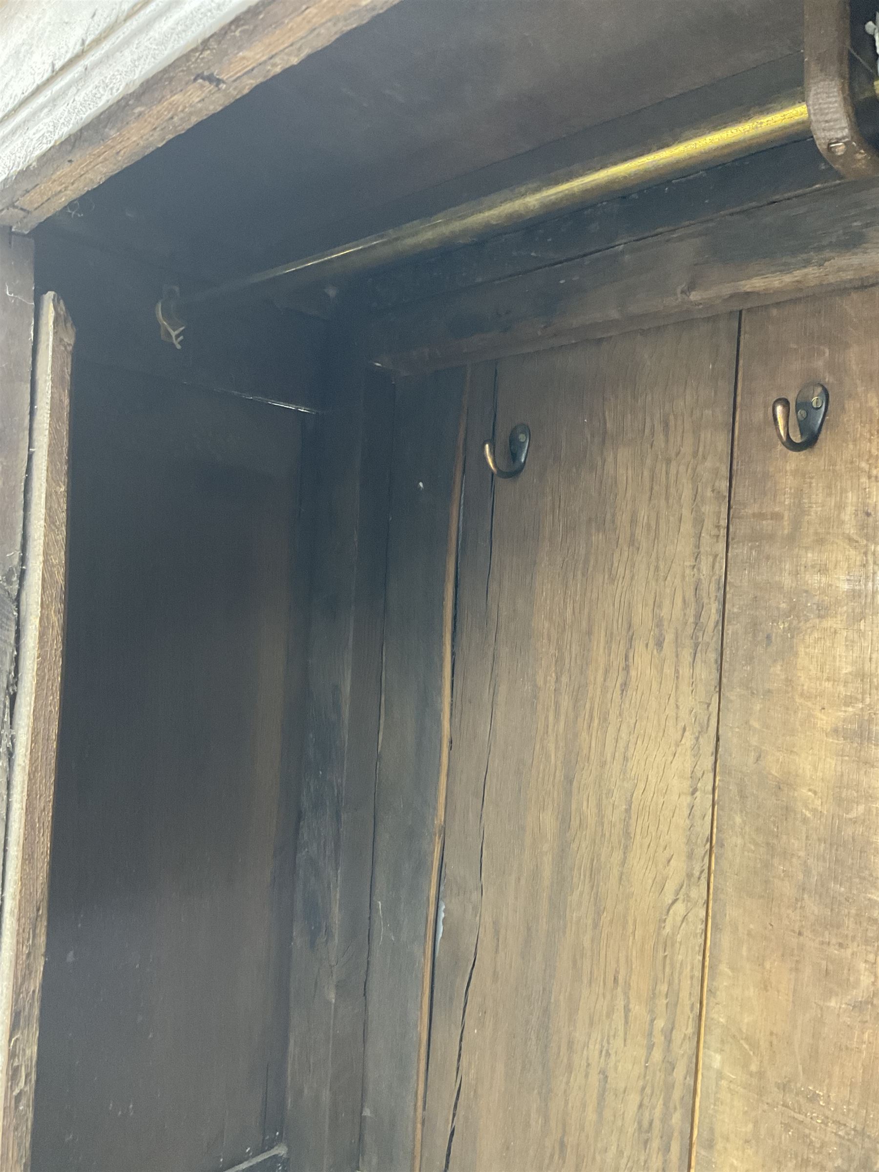 17th century and later oak hall cupboard, panelled front and sides with moulded frame, enclosed by single door with wrought metal hinges and handle, the interior fitted with hooks, on stile supports 