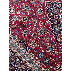 Persian Kashan crimson ground carpet, floral pattern pole medallion surrounded by trailing branches with foliate motifs and palmettes, scrolling border decorated with stylised plant motifs, within multiple guard stripes