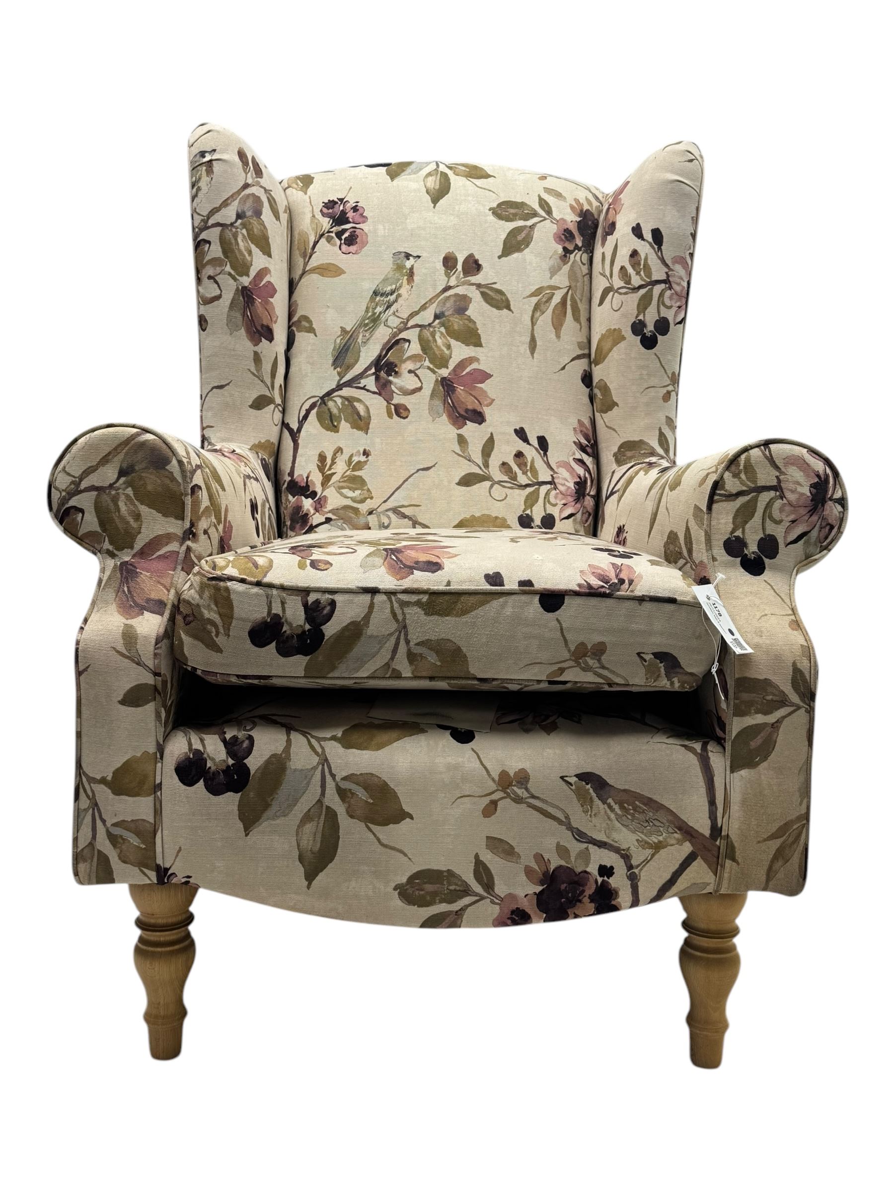 Hardwood-framed wingback armchair, upholstered in cream floral pattern fabric, on turned front feet