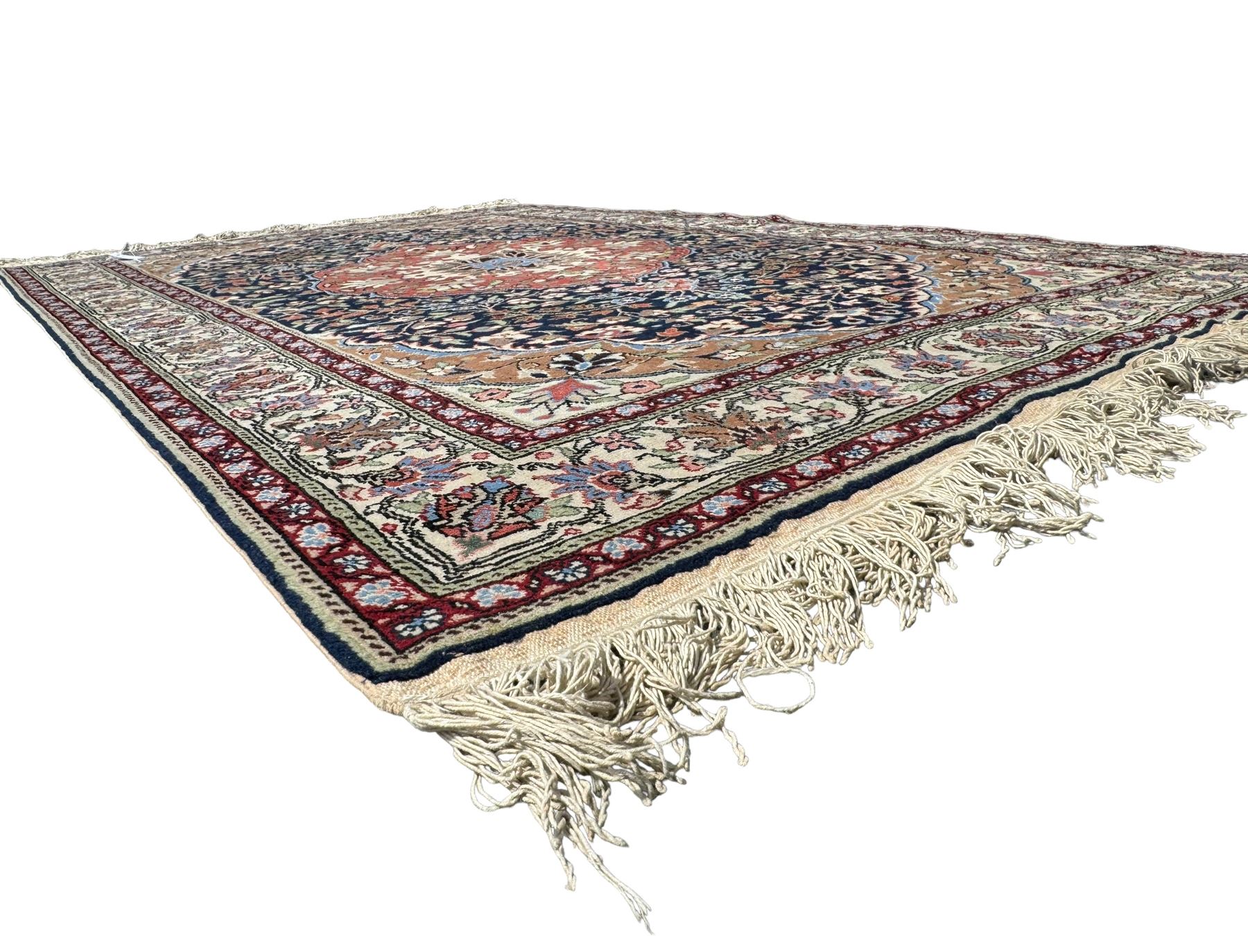 Indo-Persian indigo ground rug, the floral design peach medallion surrounded by trailing and interlaced branches and flower heads, the main border decorated with repeating stylised plant motifs within floral guard stripes 