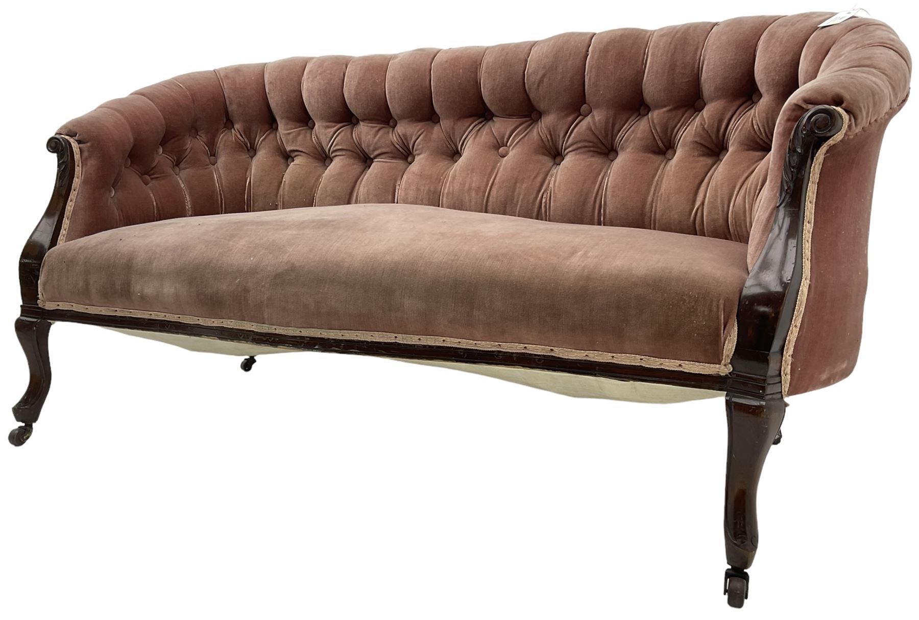 Late 19th century mahogany framed two-seat sofa, upholstered in buttoned pink fabric, on cabriole front supports, on castors 