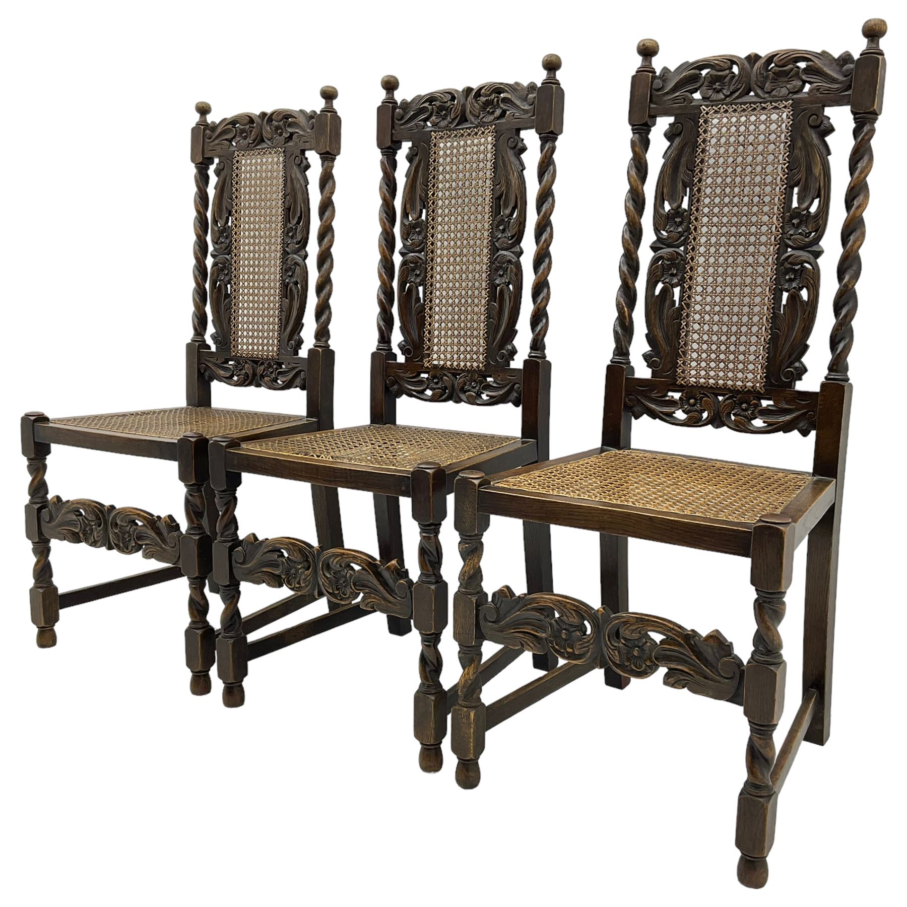 Set of seven (5+2) 19th century Carolean design oak dining chairs, scroll leaf and flower head carved cresting rail over spiral turned uprights and cane work back, the cane work seat on spiral turned supports united by plain stretchers, scrolled leaf carved middle rail 