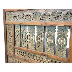 Early 20th century Javanese teak and hardwood door panel or room divider, rectangular panelled form with moulded frame and pegged construction, carved and pierced with scrolling decoration and flower head motifs, shaped and pierced splats with interlocking pattern