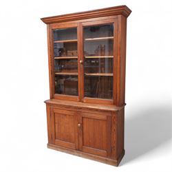 Victorian pitch pine bookcase on cupboard, glazed upper section over panelled cupboard, on...