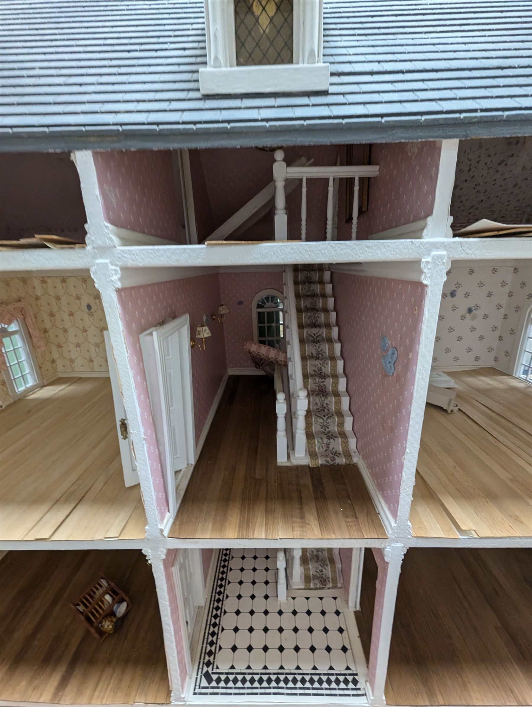 Large three storey modern dolls house, painted white with latticed windows, grey roof and metal fencing, with decorated interior, together with two dolls house garden rooms and two conservatories