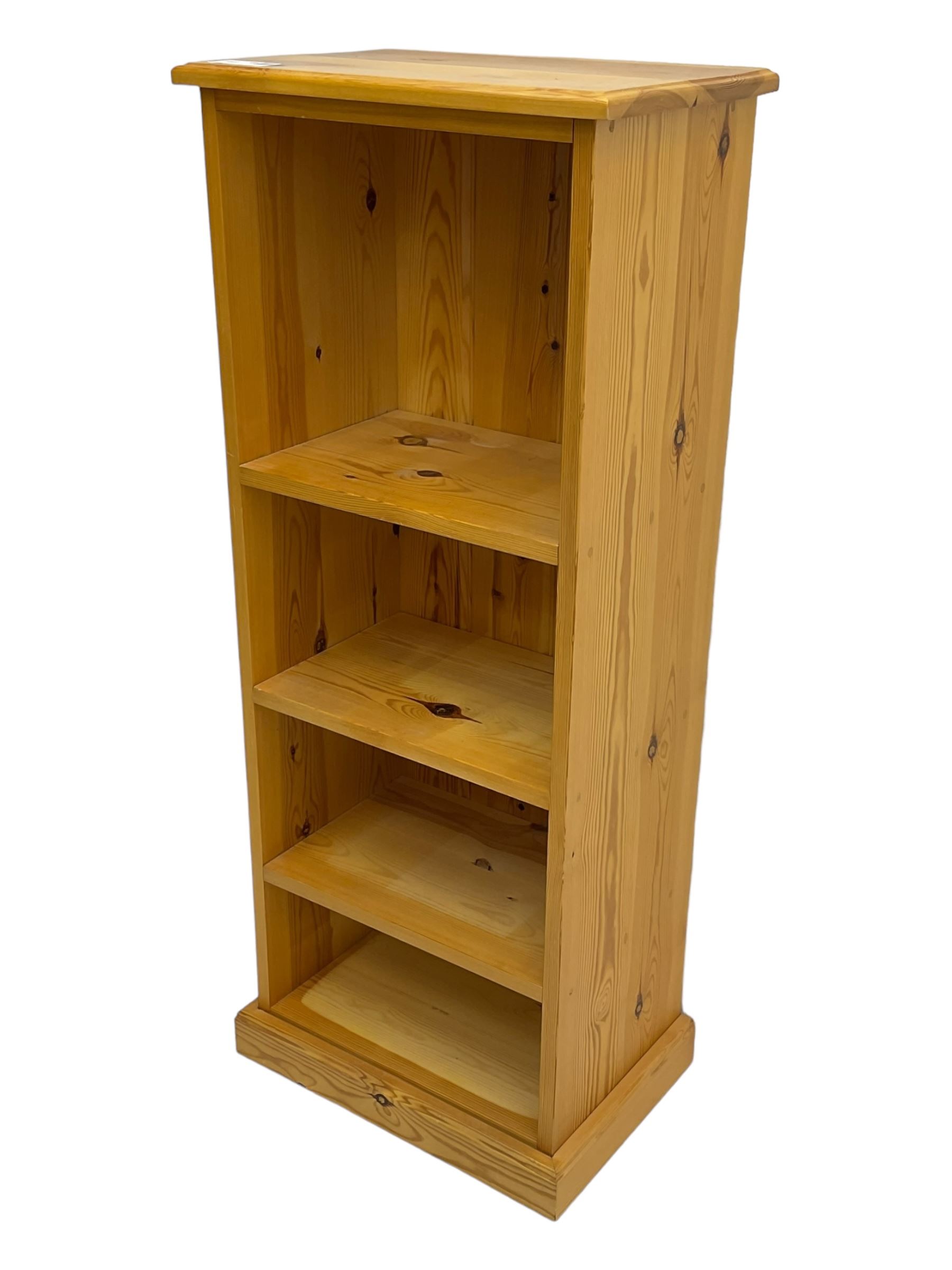 Narrow pine open bookcase, rectangular top over three shelves, on plinth base