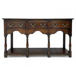 Georgian design oak dresser base, rectangular three plank top over three drawers and shaped apron, moulded drawer fronts with brass swan neck handles and circular plates, turned supports on panelled pot board base