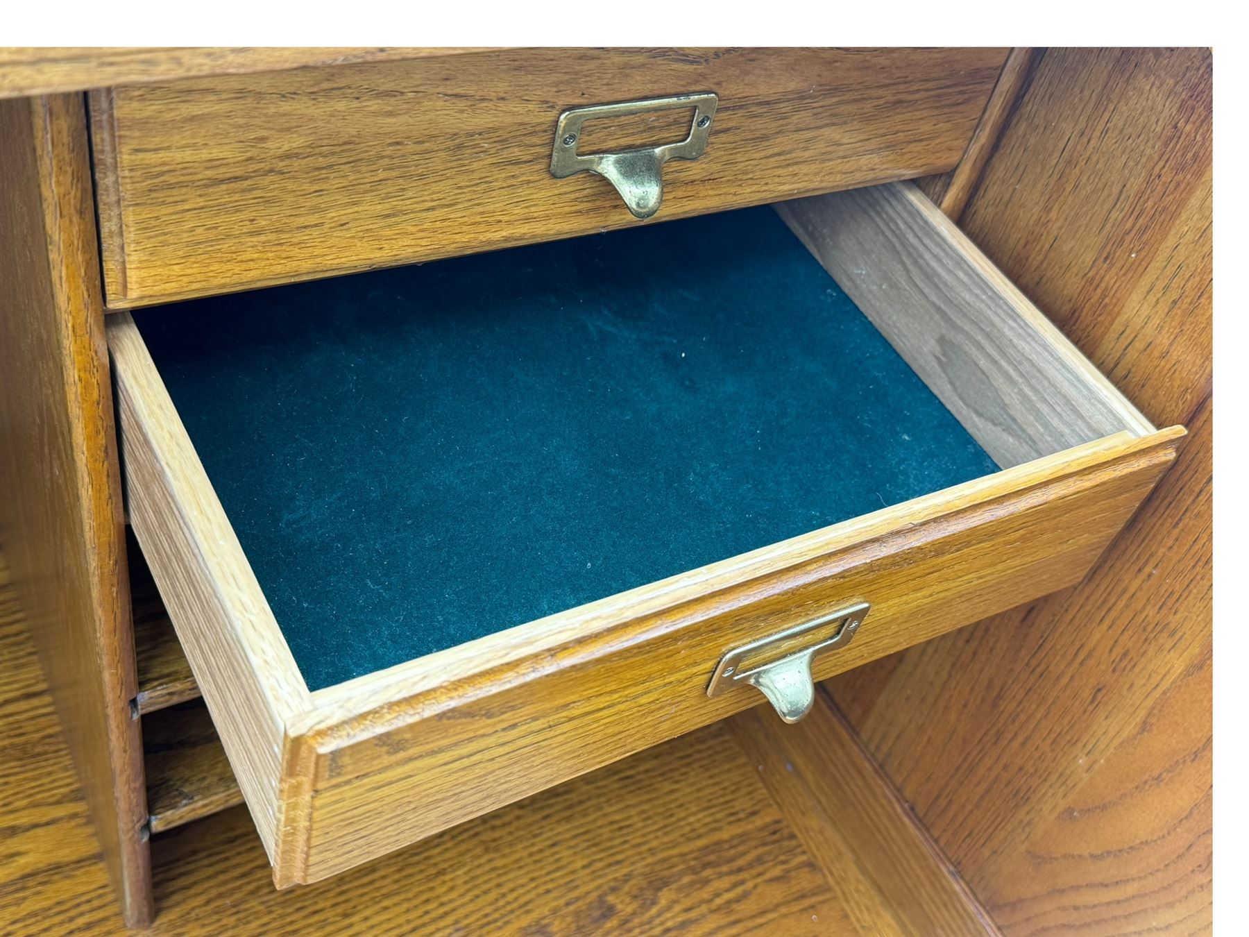 Early 20th century oak tambour roll-top desk, the top with fitted interior including drawers, pigeonholes and compartments, the twin pedestals fitted with four drawers with carved handles, supported by plinth base 