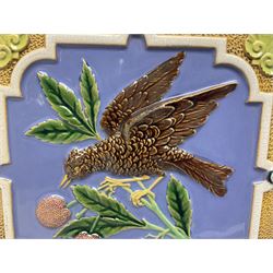 19th century Minton & Co majolica tile, decorated in relief with a bird upon a fruiting branch against a blue ground, with textured ochre border and anthemion to each corner, impressed mark verso, H19.7cm