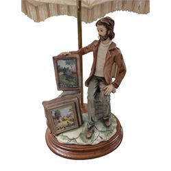 Capodimonte figural table lamp, modelled as an artist showcasing his work, with fabric tassel shade, H70cm