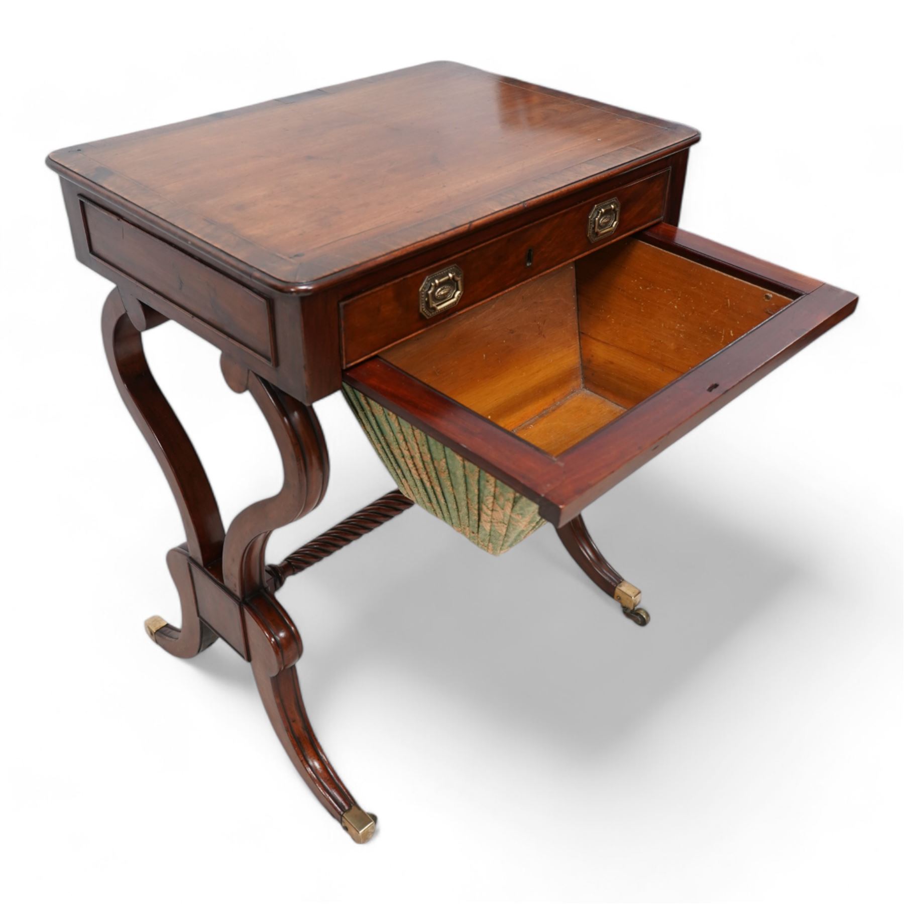 Regency mahogany work table, rectangular top with banded and moulded edge inlaid with checkered stringing, fitted with single cock-beaded drawer over upholstered sliding well, raised on scrolled twin end supports, united by a spiral-turned stretcher, on splayed supports with brass cups and castors