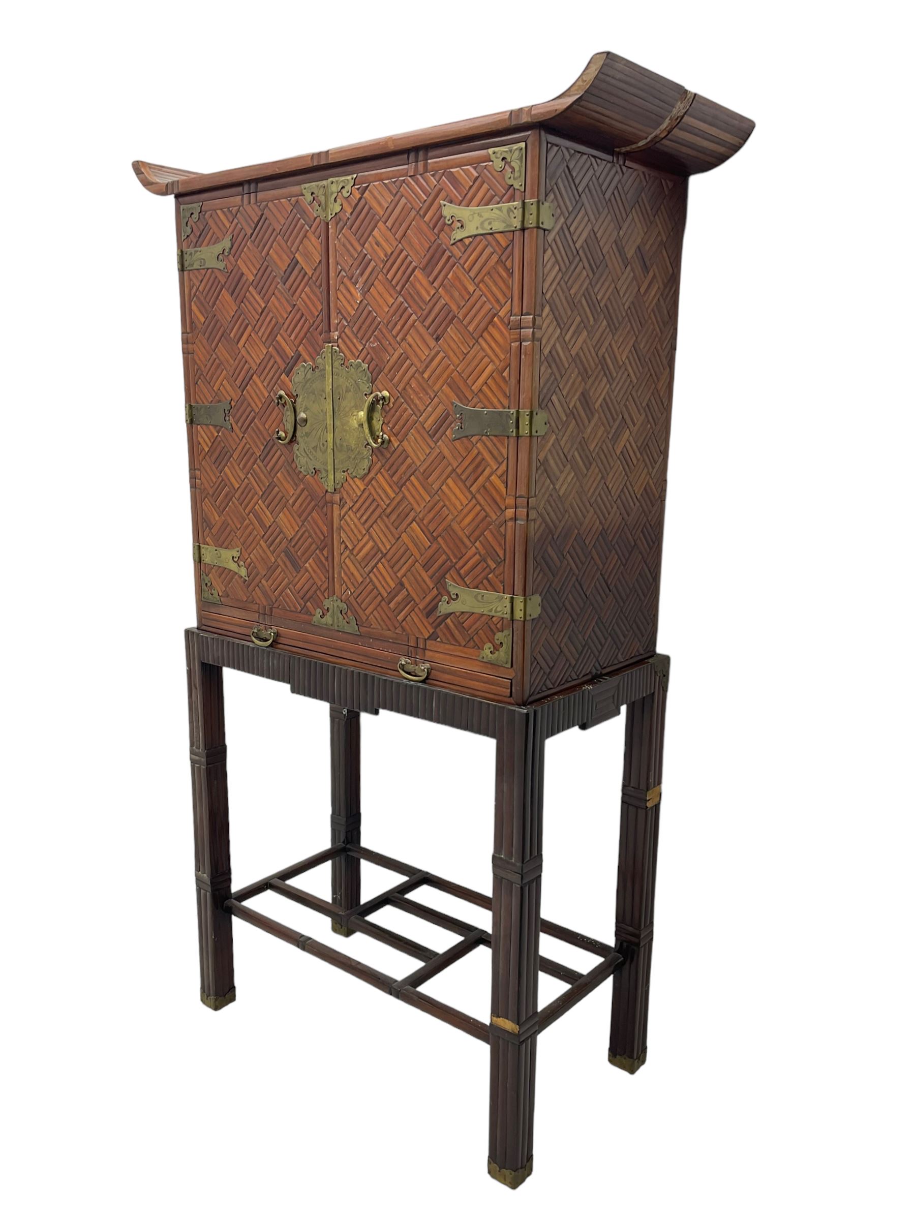 Chinese design bamboo and wood altar cabinet on stand, parquetry lattice-work bamboo, two doors with engraved metal fixtures enclosing drawers and shelf, fitted with slide, the stand pm square supports joined by a series of geometric stretchers