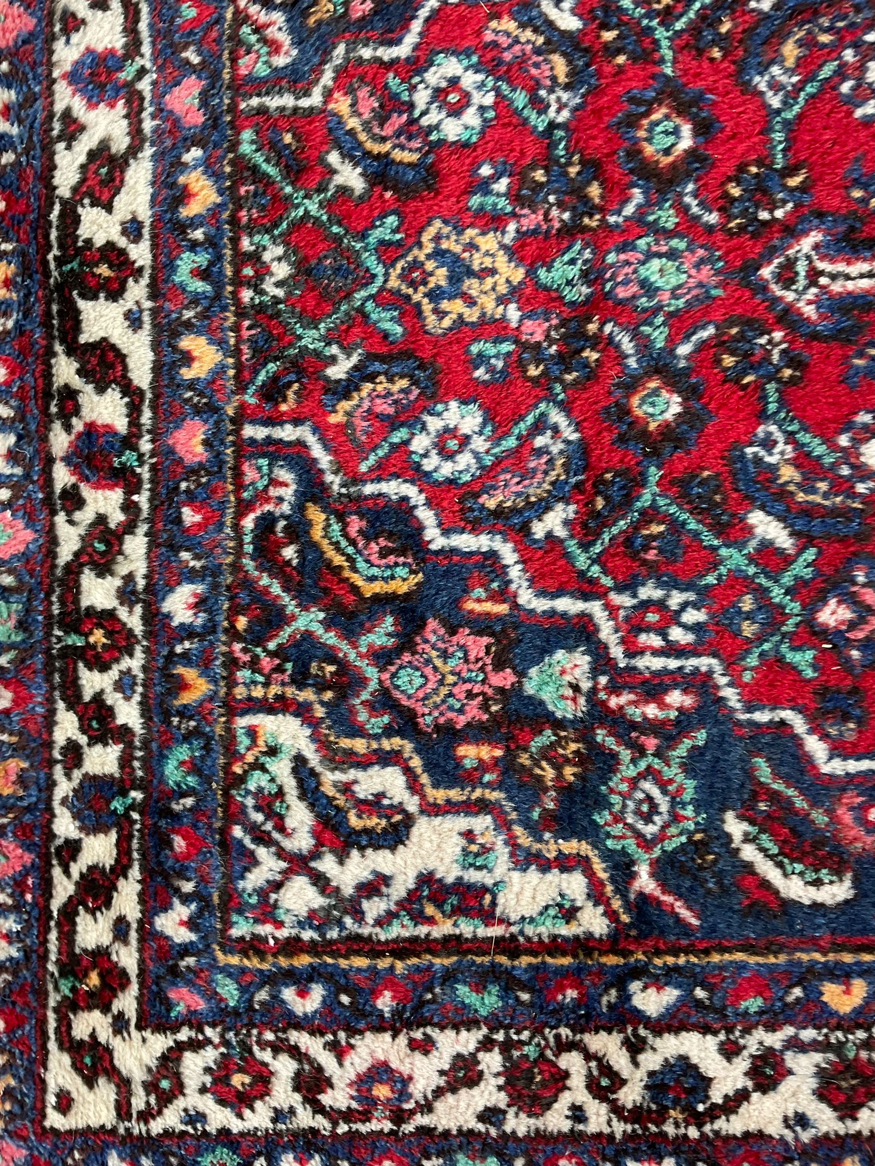 Persian Herati crimson ground rug, central ivory pole medallion surrounded by Herati motifs, with contrasting indigo spandrels, multi-band border with interlaced flowerheads