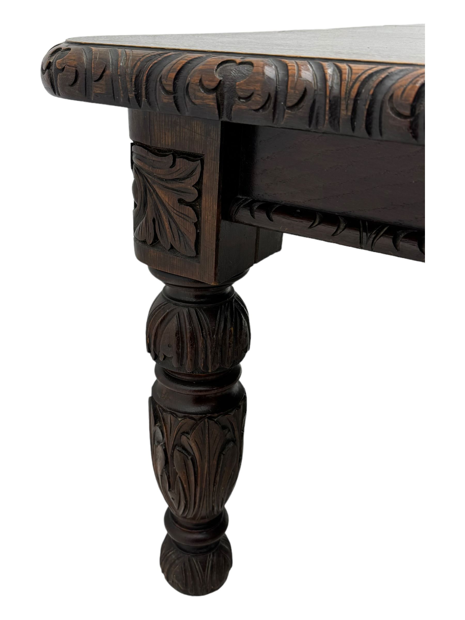 19th century heavily carved oak extending dining table, rectangular top with rounded corners and carved gadrooned edge, extending via winding mechanism with two additional leaves, raised on acanthus leaf-carved baluster supports terminating in ceramic castors