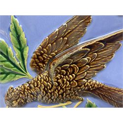 19th century Minton & Co majolica tile, decorated in relief with a bird upon a fruiting branch against a blue ground, with textured ochre border and anthemion to each corner, impressed mark verso, H19.7cm