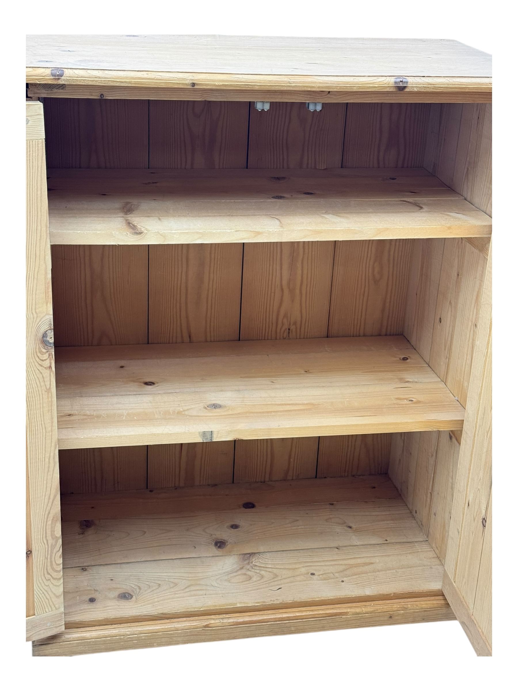 Pine cupboard, rectangular moulded top over two panelled doors enclosing two plank shelves, on plinth base