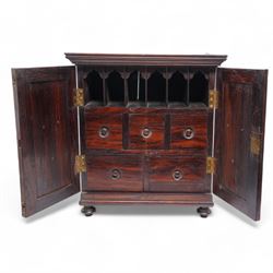 19th century rosewood spice cabinet, moulded cornice over two panelled doors decorated with fruiting foliage carved mounts, the interior fitted with a combination of small drawers, on turned feet