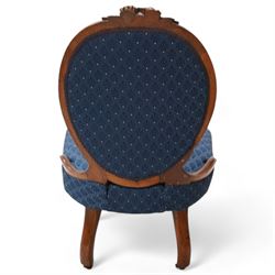 Victorian carved walnut framed nursing chair, the cresting carved with flower heads and extending foliage, upholstered in buttoned blue fabric with repeating pattern, on floral carved cabriole feet