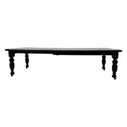 19th century heavily carved oak extending dining table, rectangular top with rounded corners and carved gadrooned edge, extending via winding mechanism with two additional leaves, raised on acanthus leaf-carved baluster supports terminating in ceramic castors