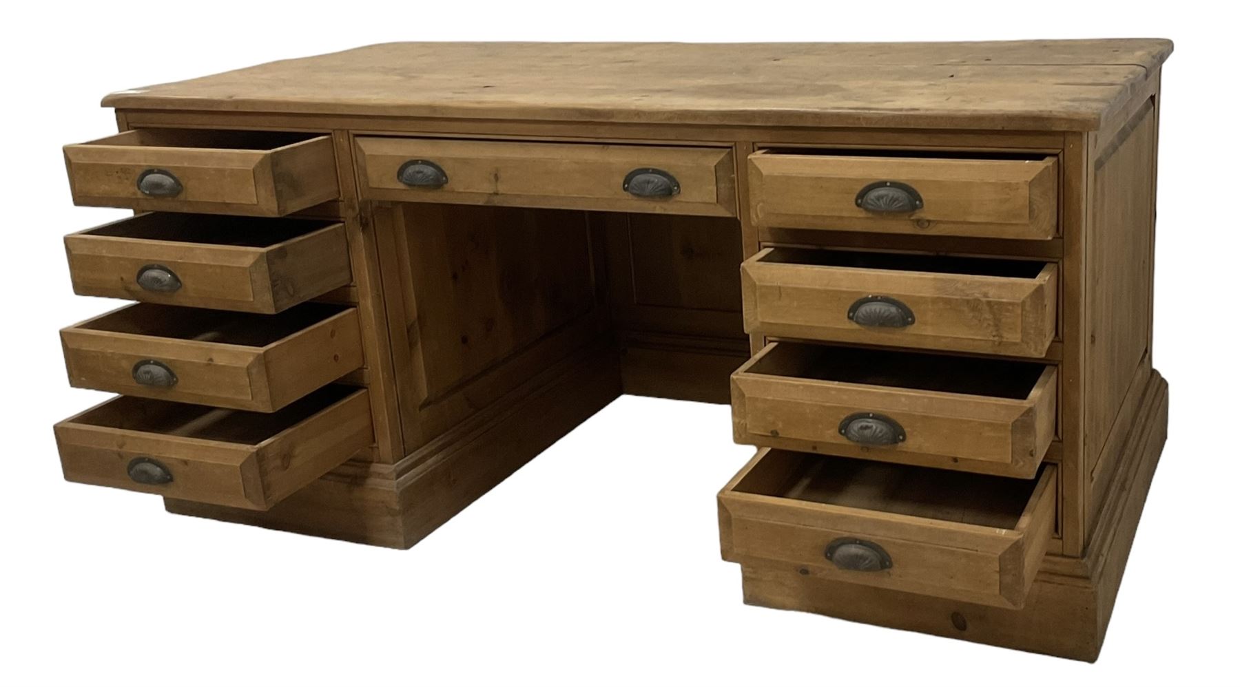 20th century waxed pine kneehole desk, rectangular top over nine drawers with cup handles, on moulded plinth base