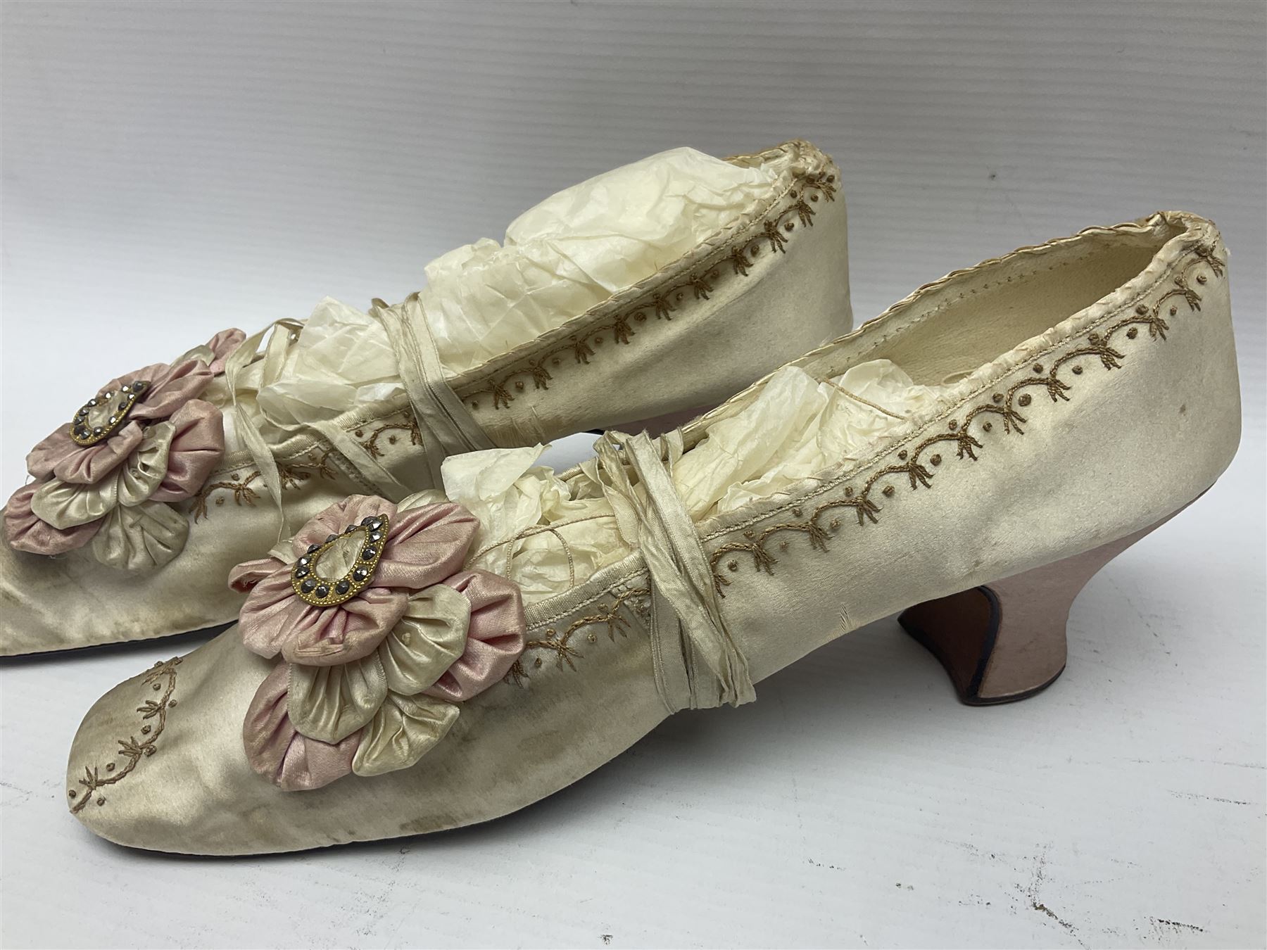 Pair of 19th century ivory silk satin ladies shoes, with rosette to the vamp, with pink silk satin heel, L23cm