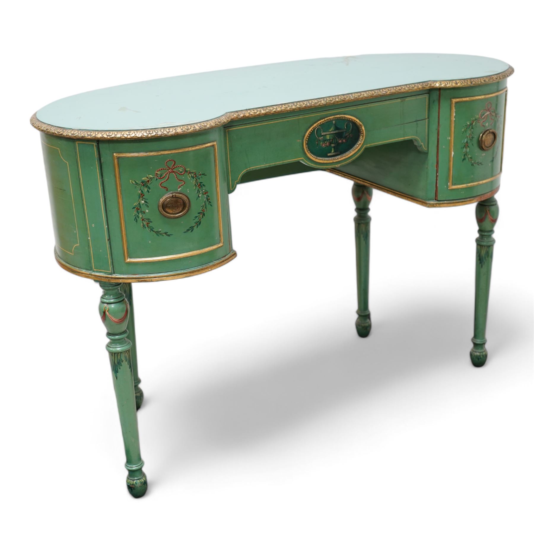 Edwardian Adam Revival green-painted and parcel gilt kneehole desk or dressing table, kidney shaped form with foliate carved edge, fitted with three drawers painted with urn and fruiting laurel wreaths with ribbon ties, on acanthus leaf and draped festoon decorated turned supports 