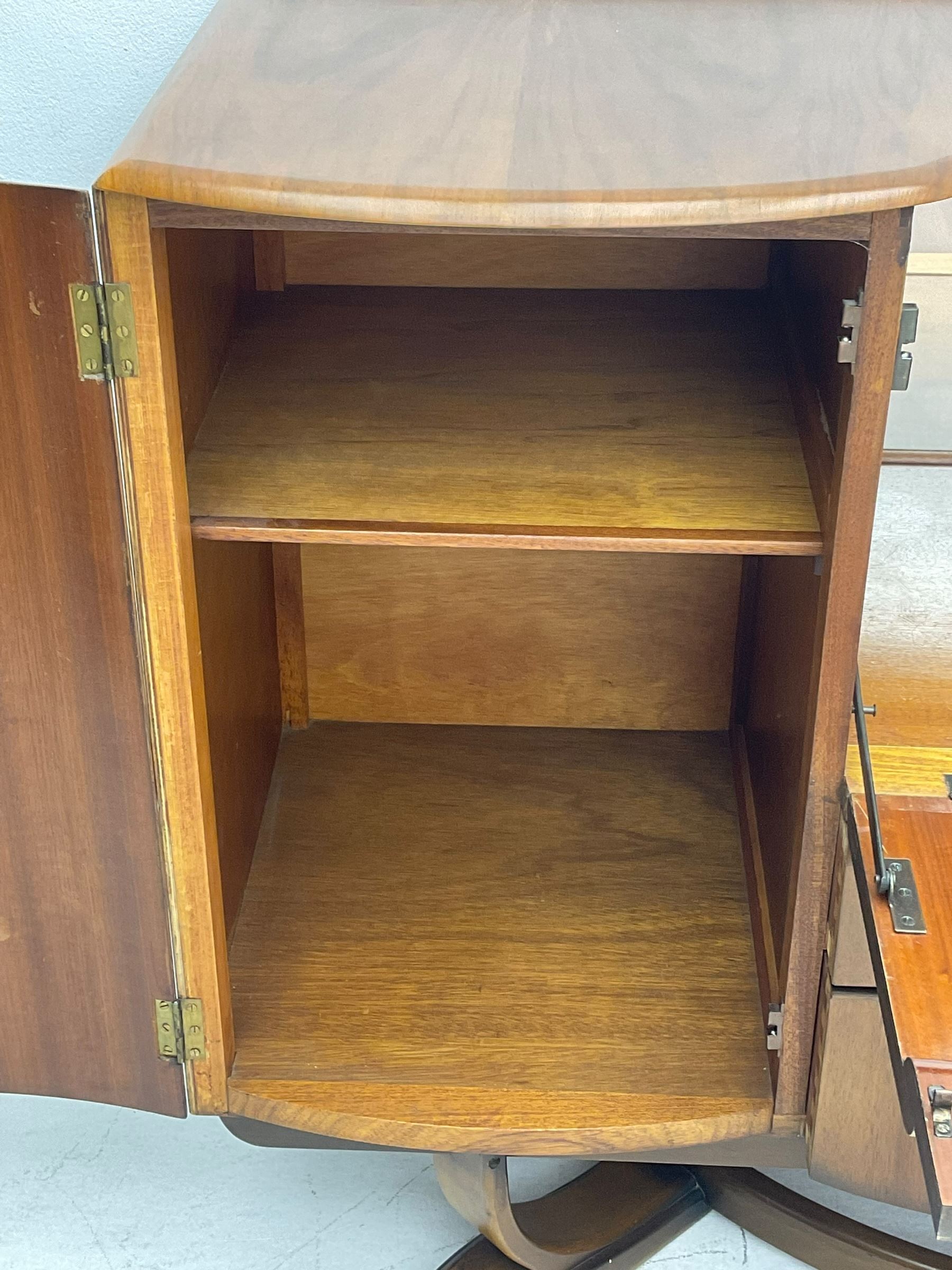 Beautility - mid-20th century walnut sideboard, fall-front with sliding top enclosing mirror interior, fitted with two drawers and flanking cupboards, on sledge feet with curved stretchers 