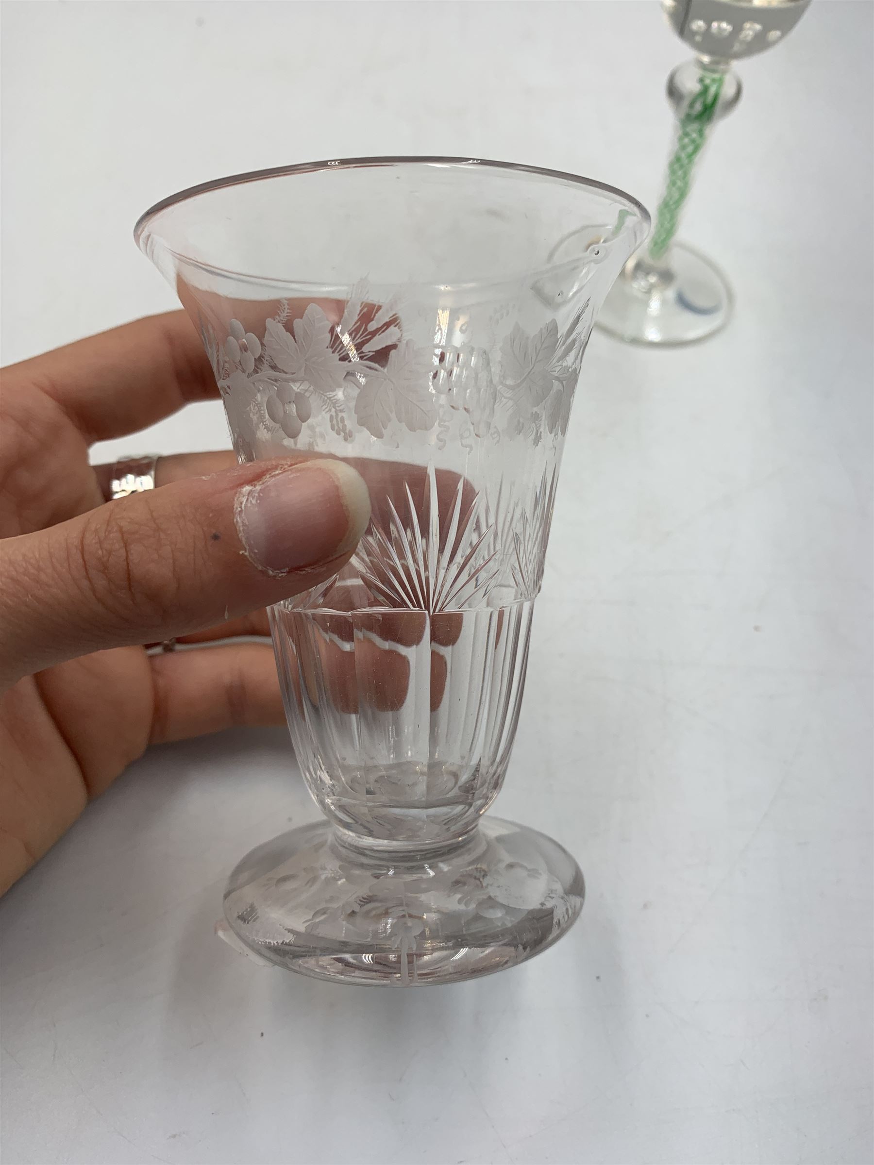 19th century continental liqueur glass, circa 1870, bucket bowl with bubble decoration, the tapered stem with green and white strands, H12.5cm; together with a Victorian aperitif glass, trumpet bowl decorated with foliate and fruiting vines, H10cm (2)