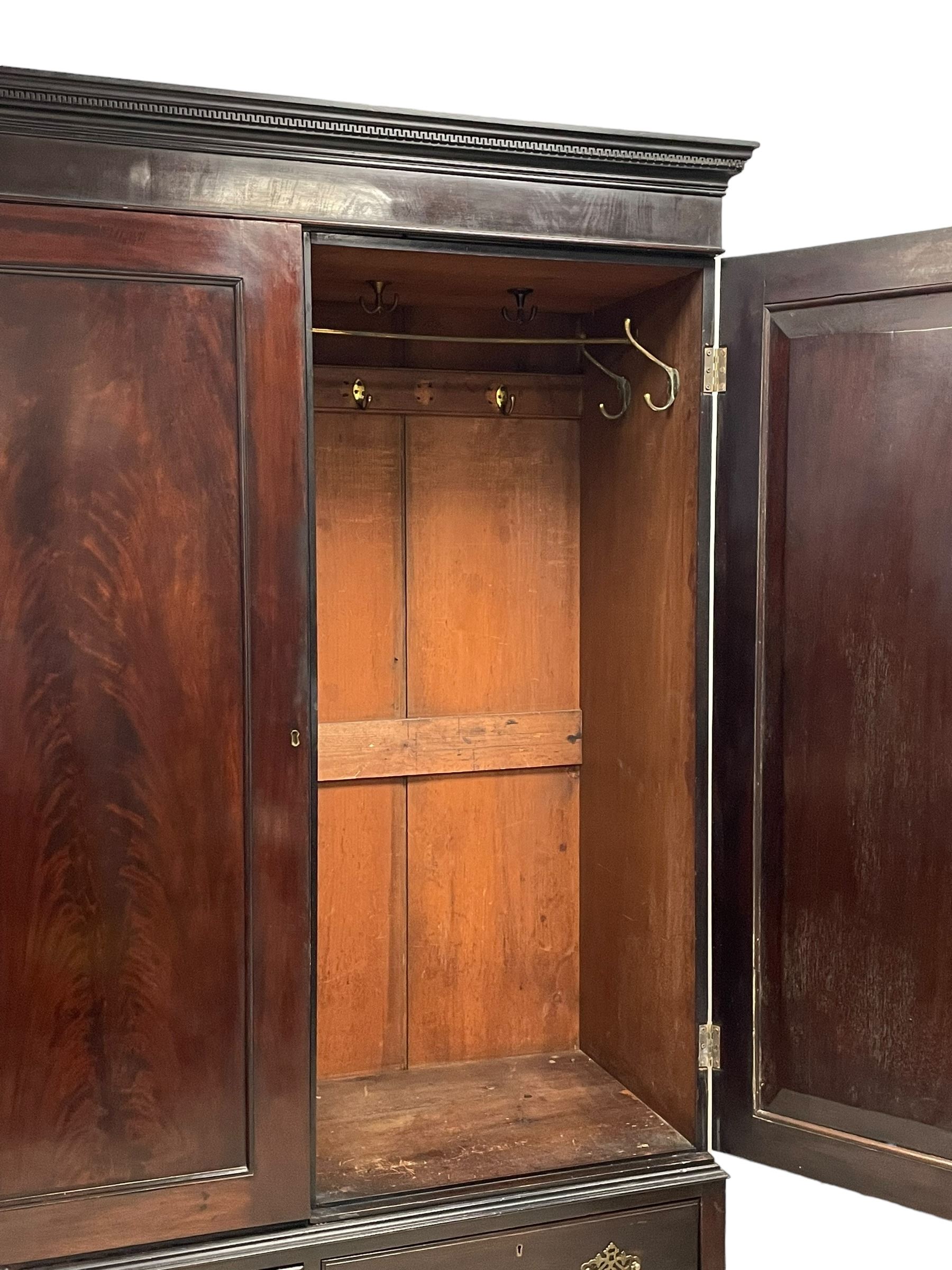 19th century Irish mahogany press wardrobe, projecting dentil cornice over two figured panelled doors, enclosing three sliding trays and hanging rail with coat hooks, fitted with two drawers to base over a shaped apron, raised on acanthus carved cabriole supports with paw feet, retailed by Millar & Beatty of Dublin, with paper labels verso, collected and restored by Michael Butler (1870-1900), impressed stamp to side and ink stamp to drawer inscribed 'M Butler collector of high-class furniture and works of art'