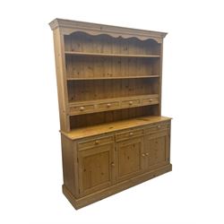 Traditional design waxed pine dresser, upper section with moulded cornice over scalloped frieze, fitted with two open shelves and four drawers, lower section with three drawers over three panelled cupboards, on plinth base