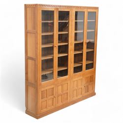 Eagleman - oak bookcase, penny moulded cresting rail over four glazed doors and four panelled doors, fitted with adjustable shelves, on moulded plinth base, panelled sides, carved with eagle signature, by Albert Jeffray, Sessay, Thirsk