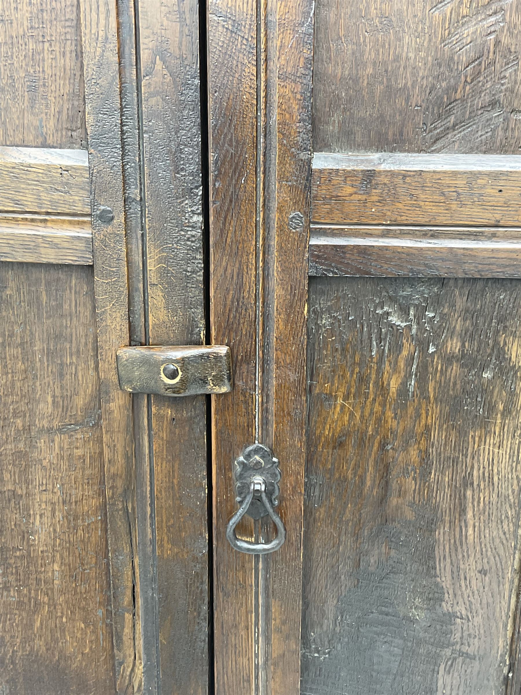 17th century and later oak hall cupboard, panelled front and sides with moulded frame, enclosed by single door with wrought metal hinges and handle, the interior fitted with hooks, on stile supports 