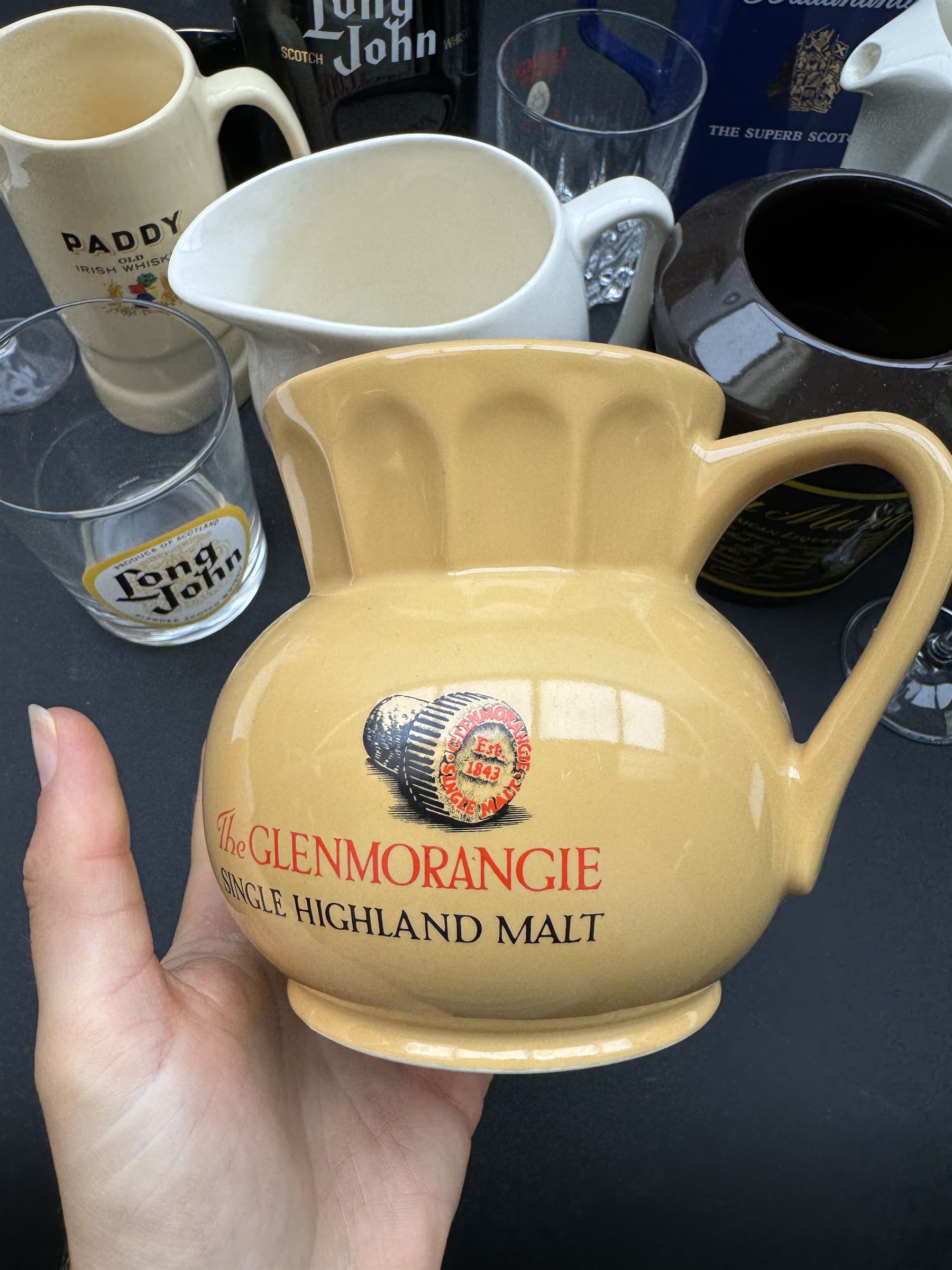 Thirteen ceramic whisky jugs bearing various advertising, including Long John, Jamesons, Ballantines etc, together with whisky glasses 