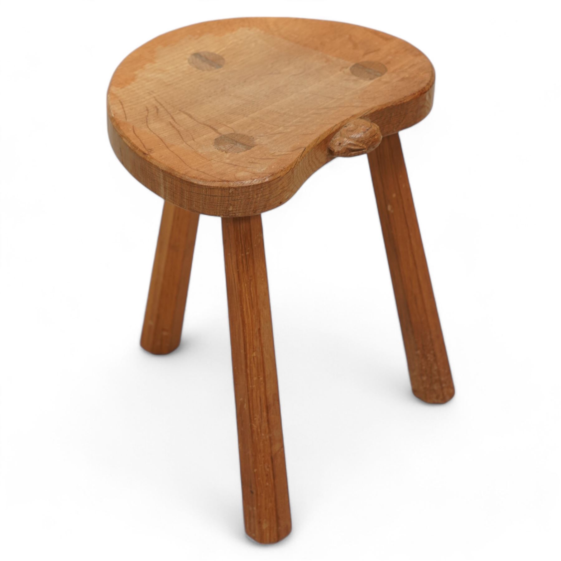 Rabbitman -  oak milking stool, dished kidney shaped top, three tapered octagonal supports, carved with rabbit signature, by Peter Heap, Wetwang