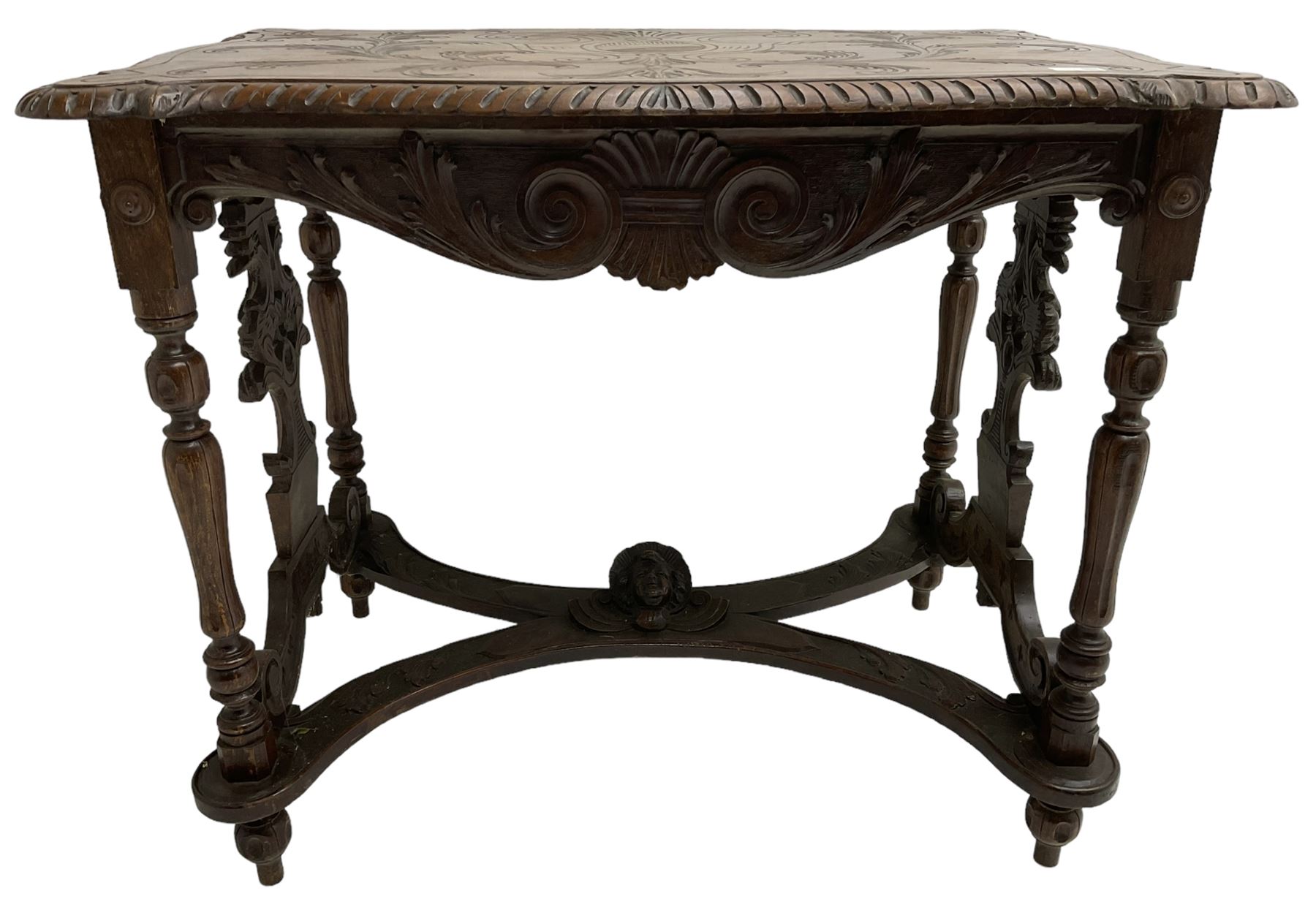 19th century walnut centre table, shaped top carved with central cartouche and extending scrolled foliage, the shaped frieze rails carved with scrolling acanthus leaves, turned supports with central end supports carved with flower heads and scrolls, curved x-framed stretcher carved with a central mask depicting a girl in a bonnet, on turned and carved feet