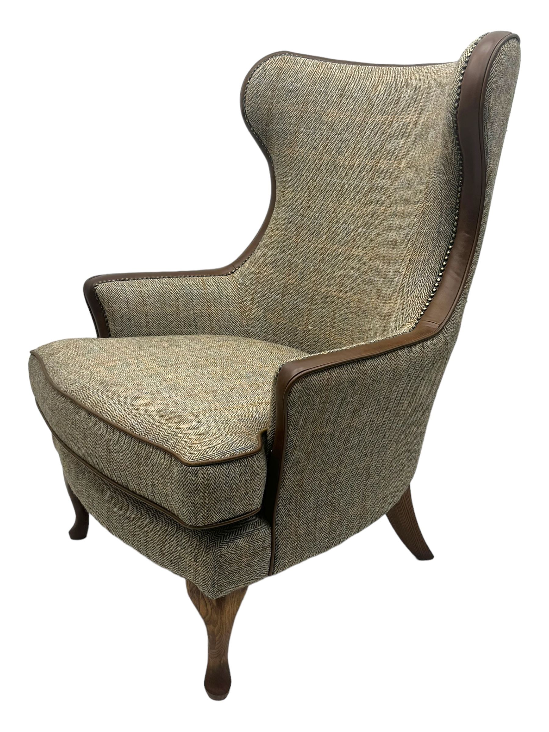 Wood Bros - contemporary wingback armchair, high back with curved wings upholstered in herringbone patterned fabric, accented with leather trim and brass nailhead studs, resting on cabriole front feet 