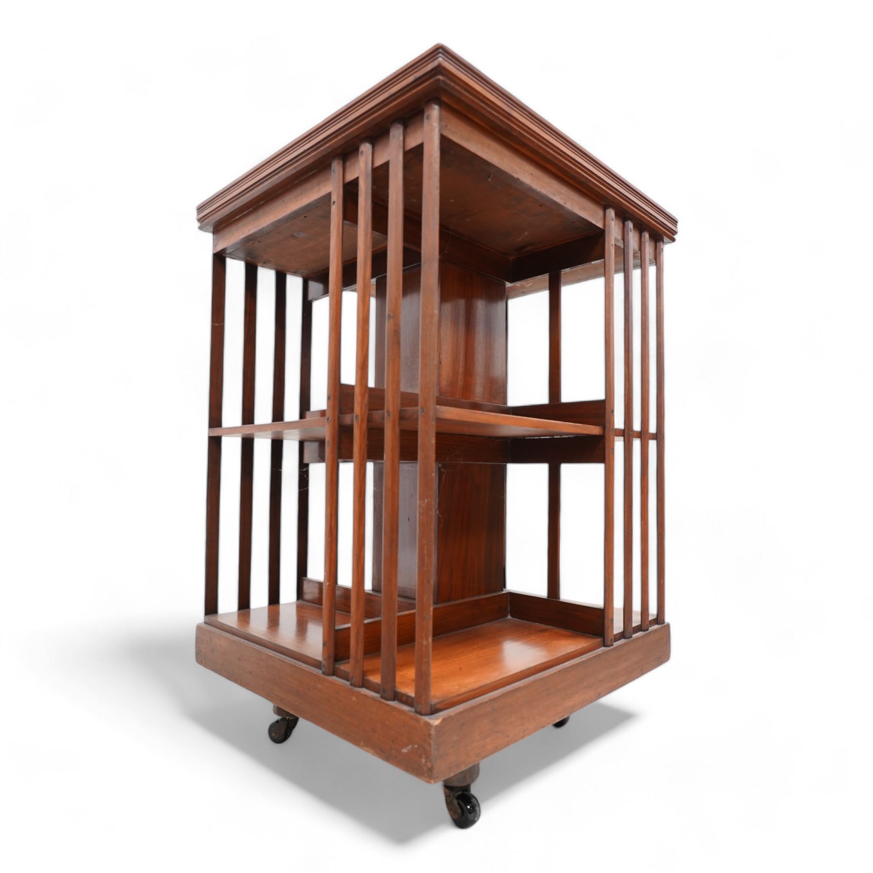 Edwardian mahogany revolving bookcase, square form with moulded top, two tiers with vertical moulded slats, on brass and ceramic castors 