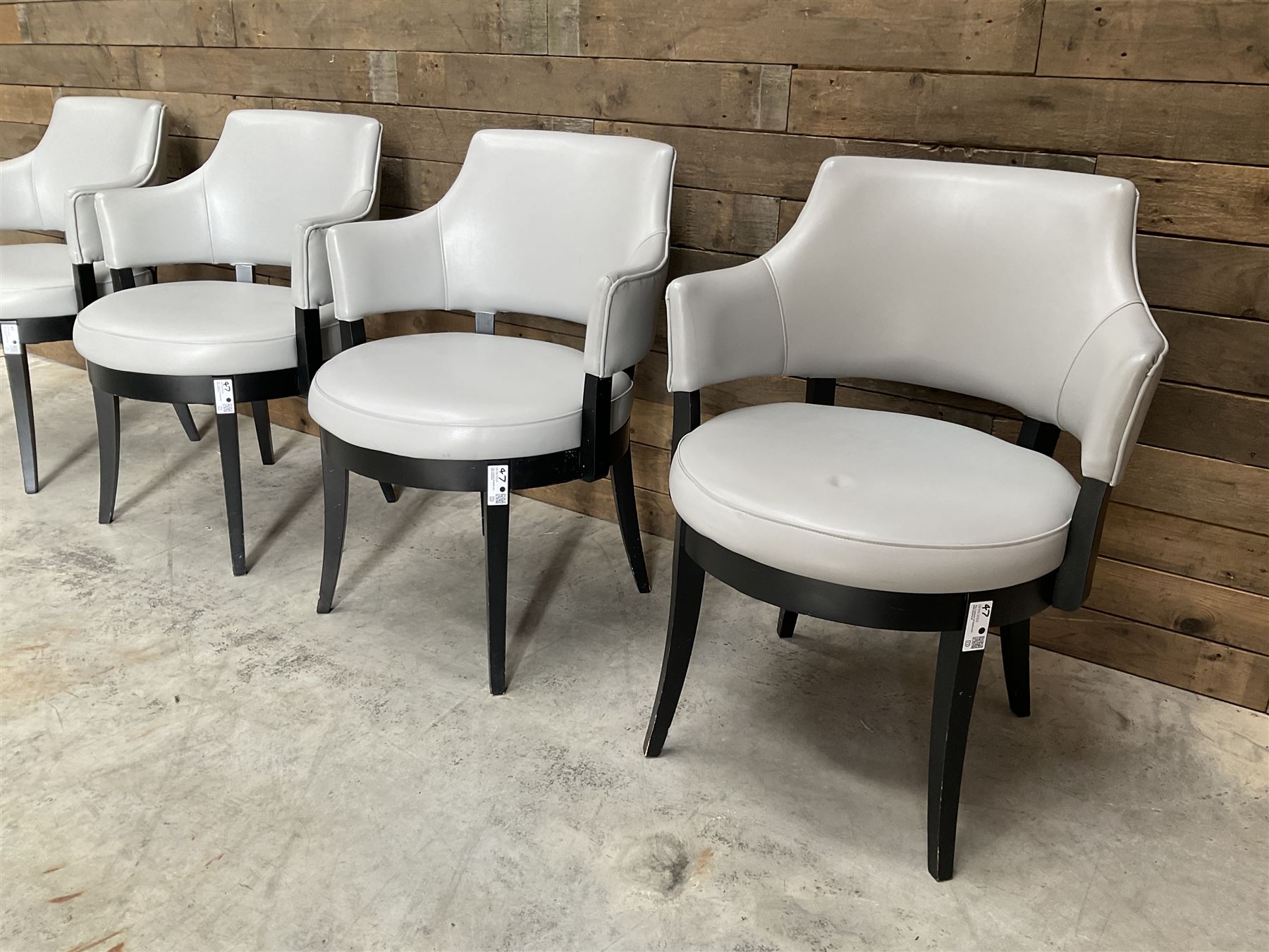 Four ebonised framed tub shaped armchairs, upholstered in grey fabric