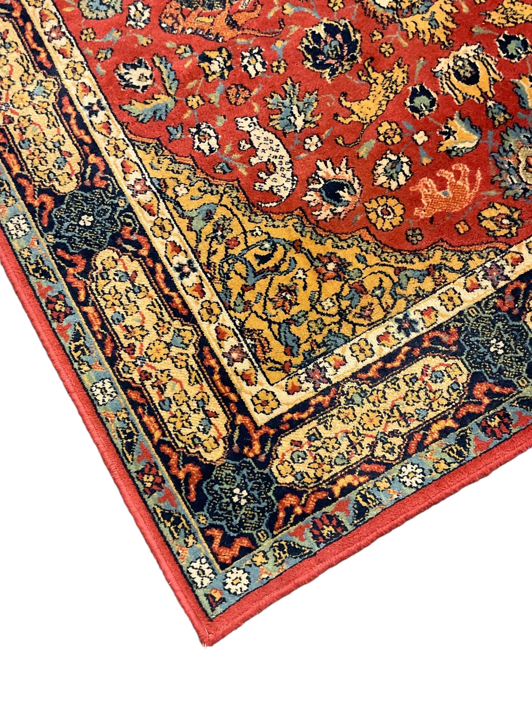 Persian design red ground rug, decorated with plant and animal motifs, the border decorated with floral design panels with guards