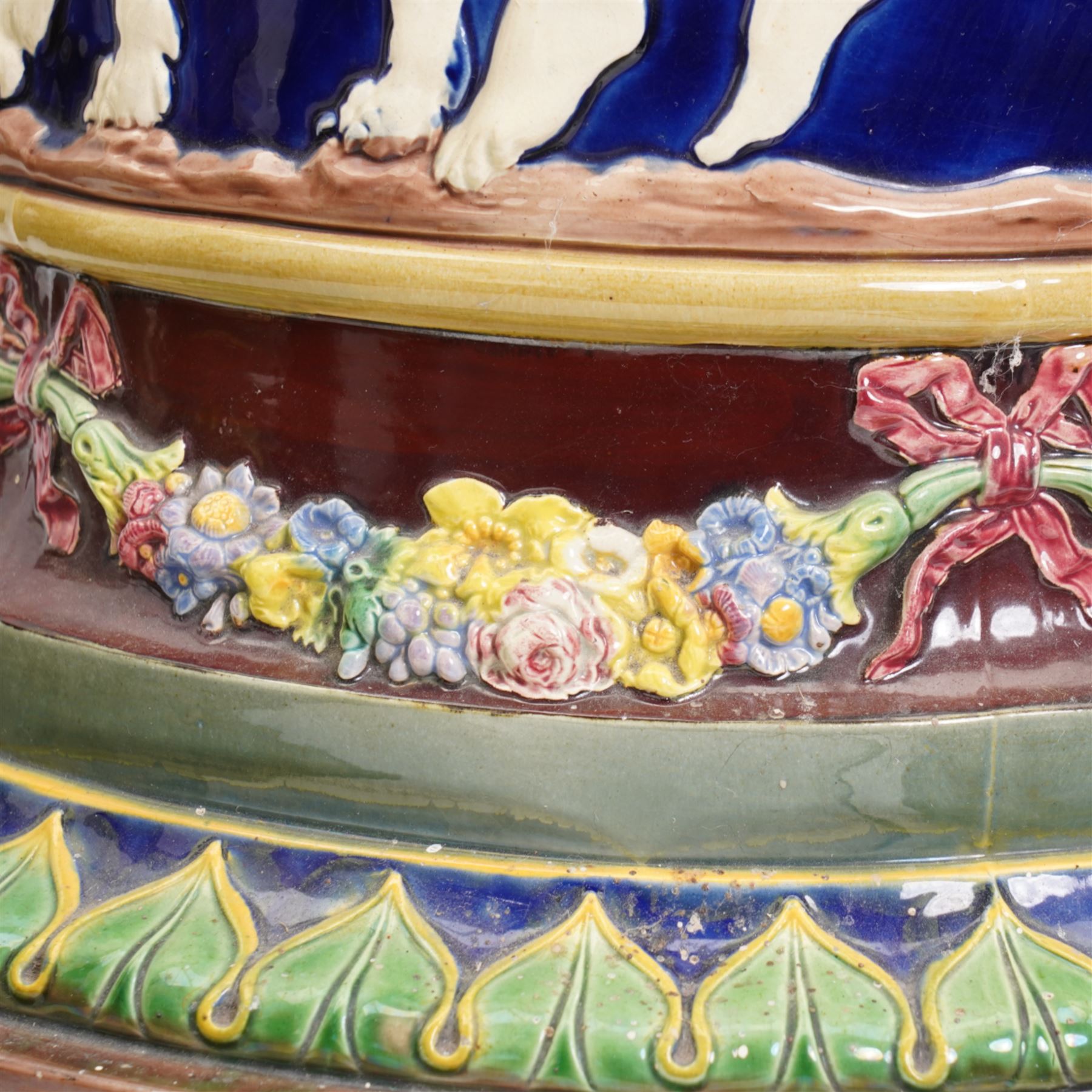 Late Victorian Copeland Majolica pedestal, circa 1850 - 1870, the cylindrical column moulded in relief with a frieze of Classical figures in cream on a cobalt glazed ground, the borders with coloured flower garlands and tortoiseshell mottled top, H62cm x D35cm