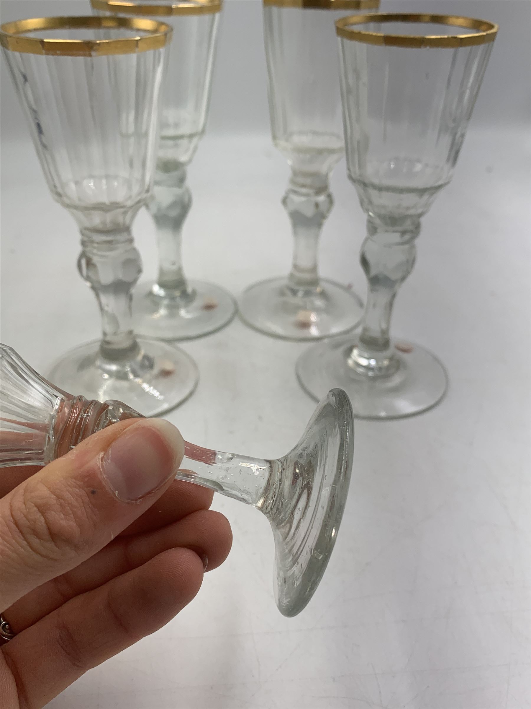 Set of four 19th century Baccarat liqueur/sherry glasses, circa 1820, with panelled bucket bowls and gilt rims, engraved CEG, to faceted knopped stems, together with another smaller example, H14cm and H12cm (5)