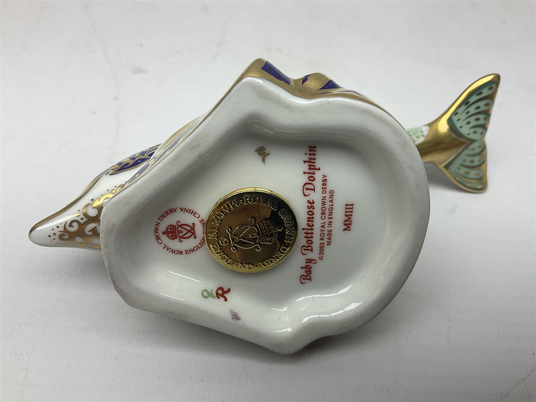 Three Royal Crown Derby paperweights, comprising Bottlenose Dolphin, Baby Bottlenose Dolphin and Striped Dolphin, all with gold stoppers 