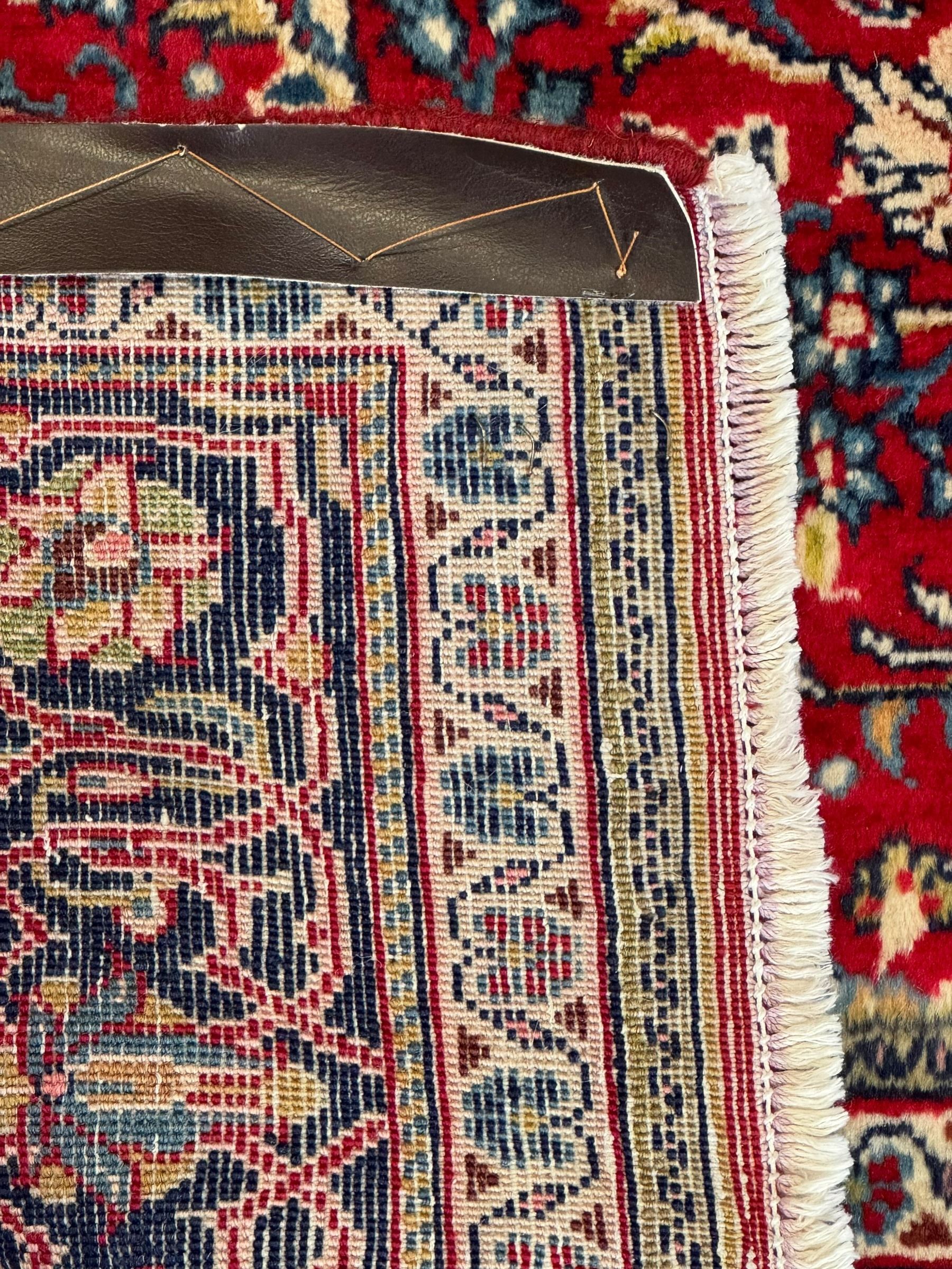 North west Persian Sarouk crimson ground rug, central floral medallion surrounded by scrolling branches decorated with foliage and stylised plant motifs, the main border decorated with repeating scrolling design with floral motifs, within guard stripes 