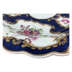 18th century Worcester tea caddy, of oval form and painted in the Kakiemon palette with reserves of flowers against a blue scale ground, H14cm together with a similar Worcester circular dish, painted with floral sprays, within a scalloped edge, blue crescent mark beneath, D19cm (2)