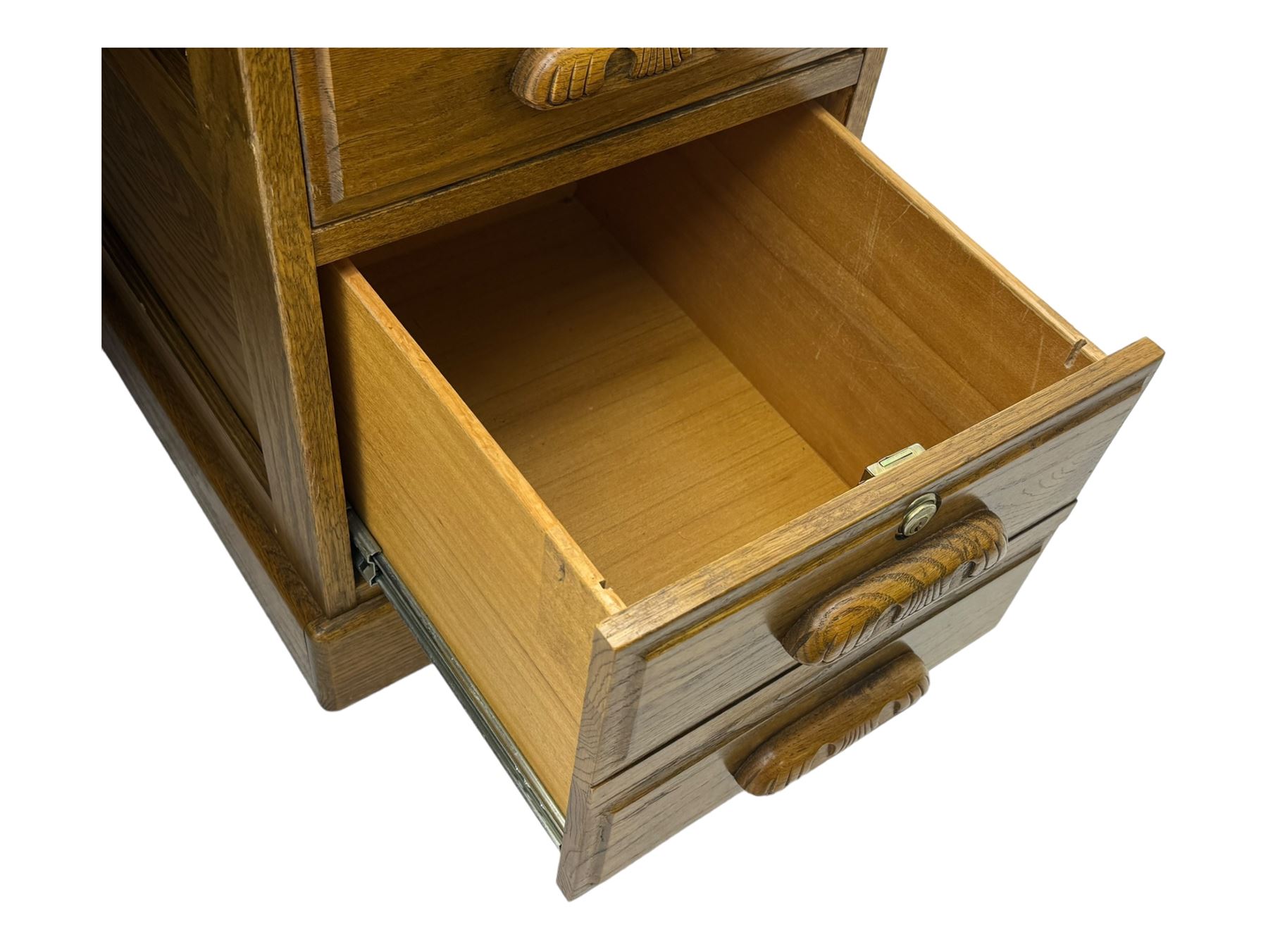 Early 20th century oak tambour roll-top desk, the top with fitted interior including drawers, pigeonholes and compartments, the twin pedestals fitted with four drawers with carved handles, supported by plinth base 