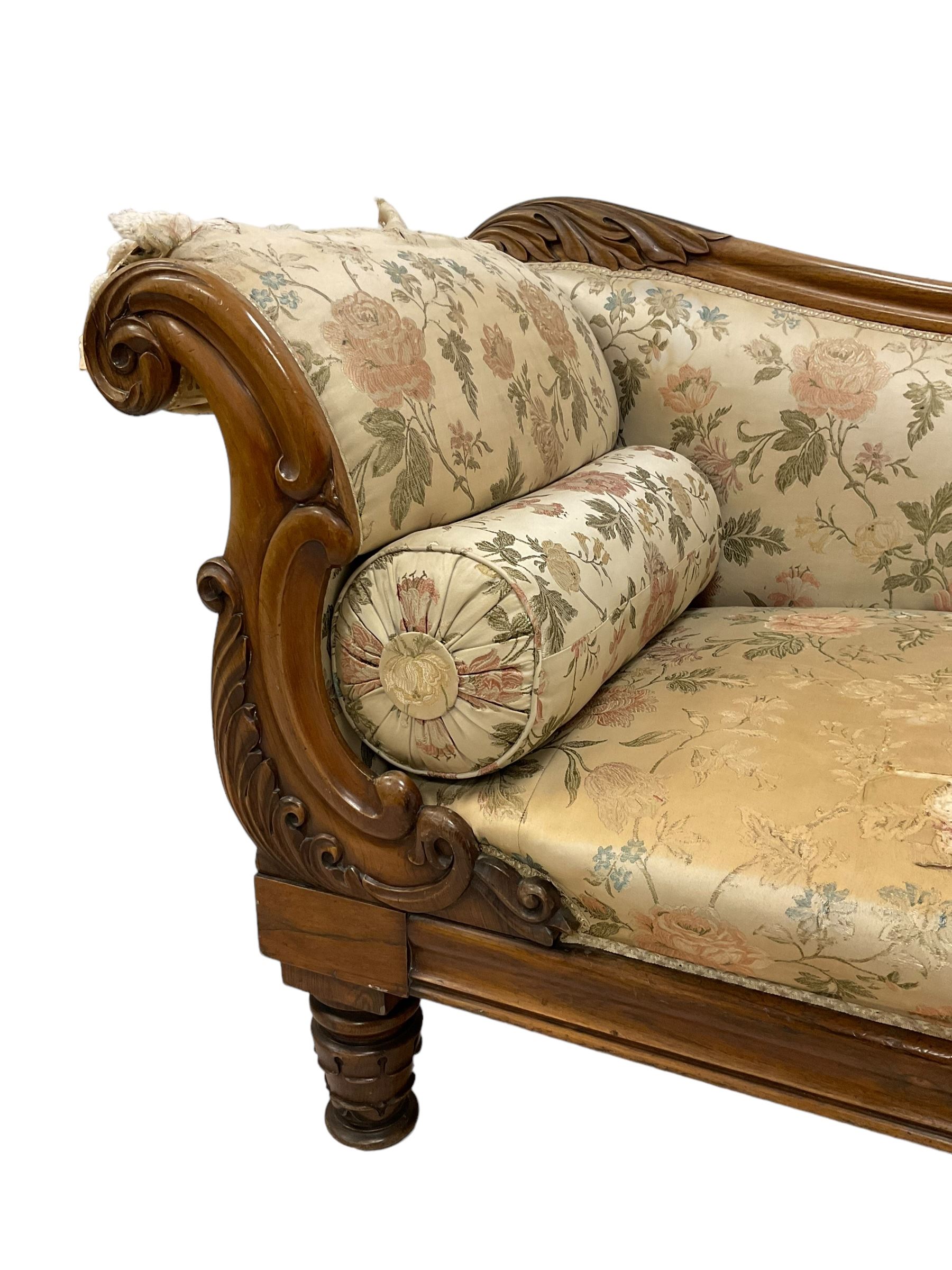 Victorian rosewood chaise longue, rolled back rest and shaped cresting rail carved with curled leaves and scrolls, upholstered in floral pattern fabric with bolster cushion, moulded lower rail with rectangular panel, on turned and lappet carved feet