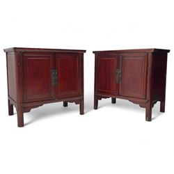 Pair of early 20th century Chinese red lacquered elm storage cupboards, rectangular top over two panelled doors, fitted with two internal drawers, on square supports with curved outer edge, panelled sides