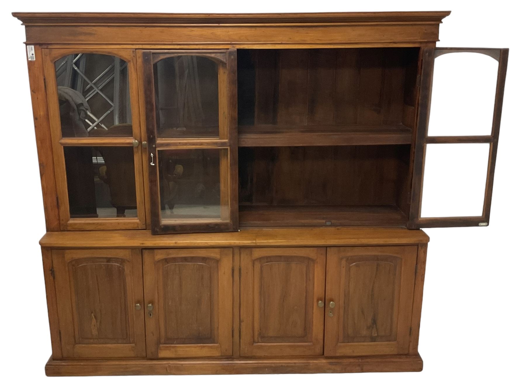 Mid-to-late 20th century Burmese teak wall cabinet, four glazed doors over four panelled doors, on moulded plinth base 