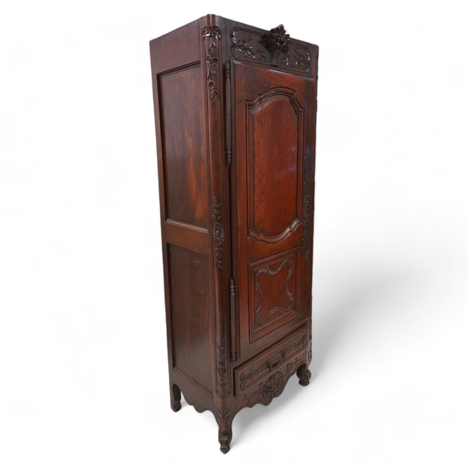 19th century French walnut hall cupboard, the frieze carved with a bouquet of flowers and trailing foliate decoration, enclosed by single panelled door over single drawer, the curved outer corners decorated with trailing leafy branches and flower heads, shaped apron with scroll carved cabriole feet 