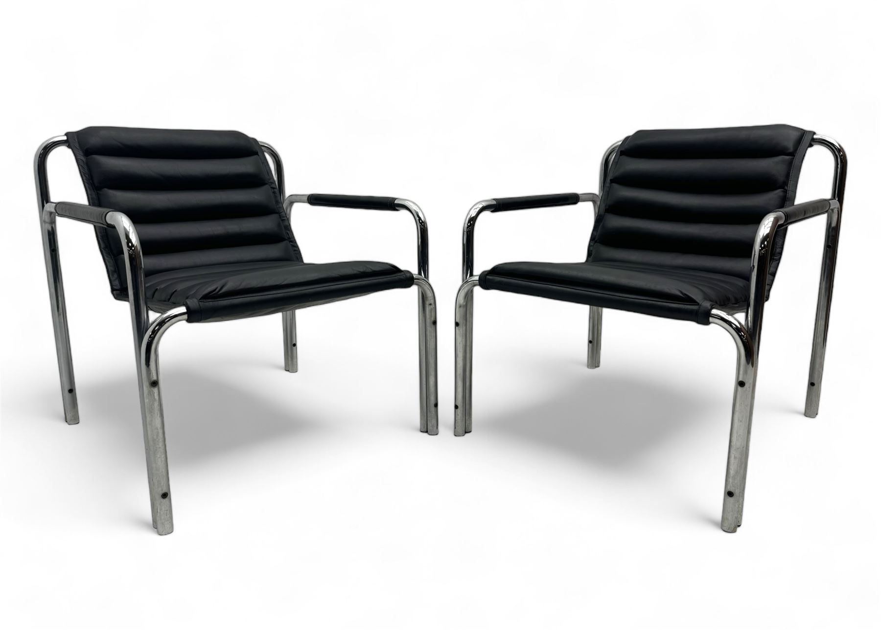 Baroumand Designs - pair of mid 20th century modernist armchairs, slung black leather seat with horizontal channel tufting, tubular chrome frame with curved arms, raised on tubular supports